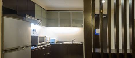 A compact kitchen with a refrigerator, microwave, toaster, and sink.