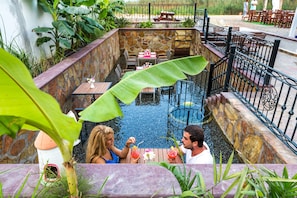 Un patio al aire libre con paredes de piedra, piscina y mesas y sillas.