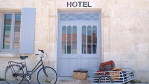 A stone building with a sign that reads "HOTEL" above a white door with decorative glass panels. - Hotel Napoléon (Ile-d'Aix)