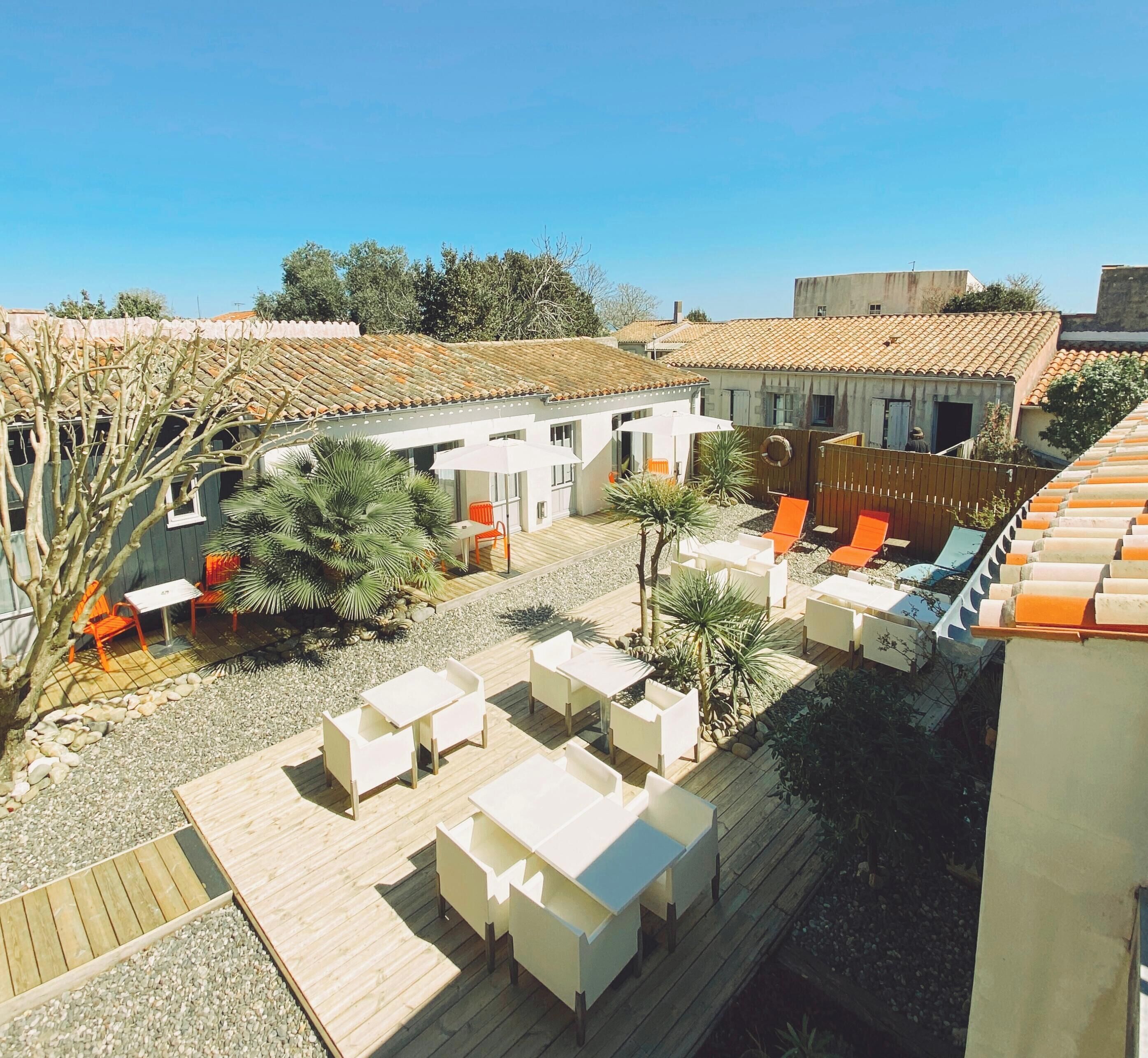 Un patio con mobiliario exterior, una piscina y un edificio con techo de tejas.