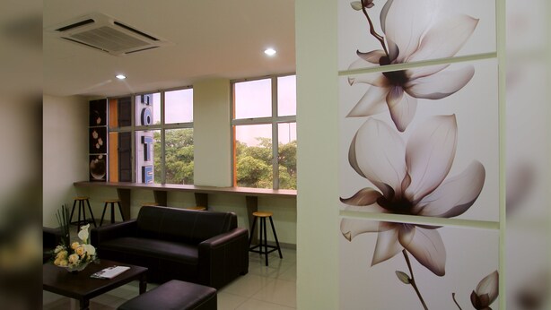 A modern living room with a sofa, coffee table, and a decorative wall with floral artwork. - Max Inn Suite Hotel (Batu Pahat)