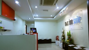 A reception area with a reception desk, a TV, a fire extinguisher, and a sign that reads "Max Inn Suite". - Max Inn Suite Hotel (Batu Pahat)
