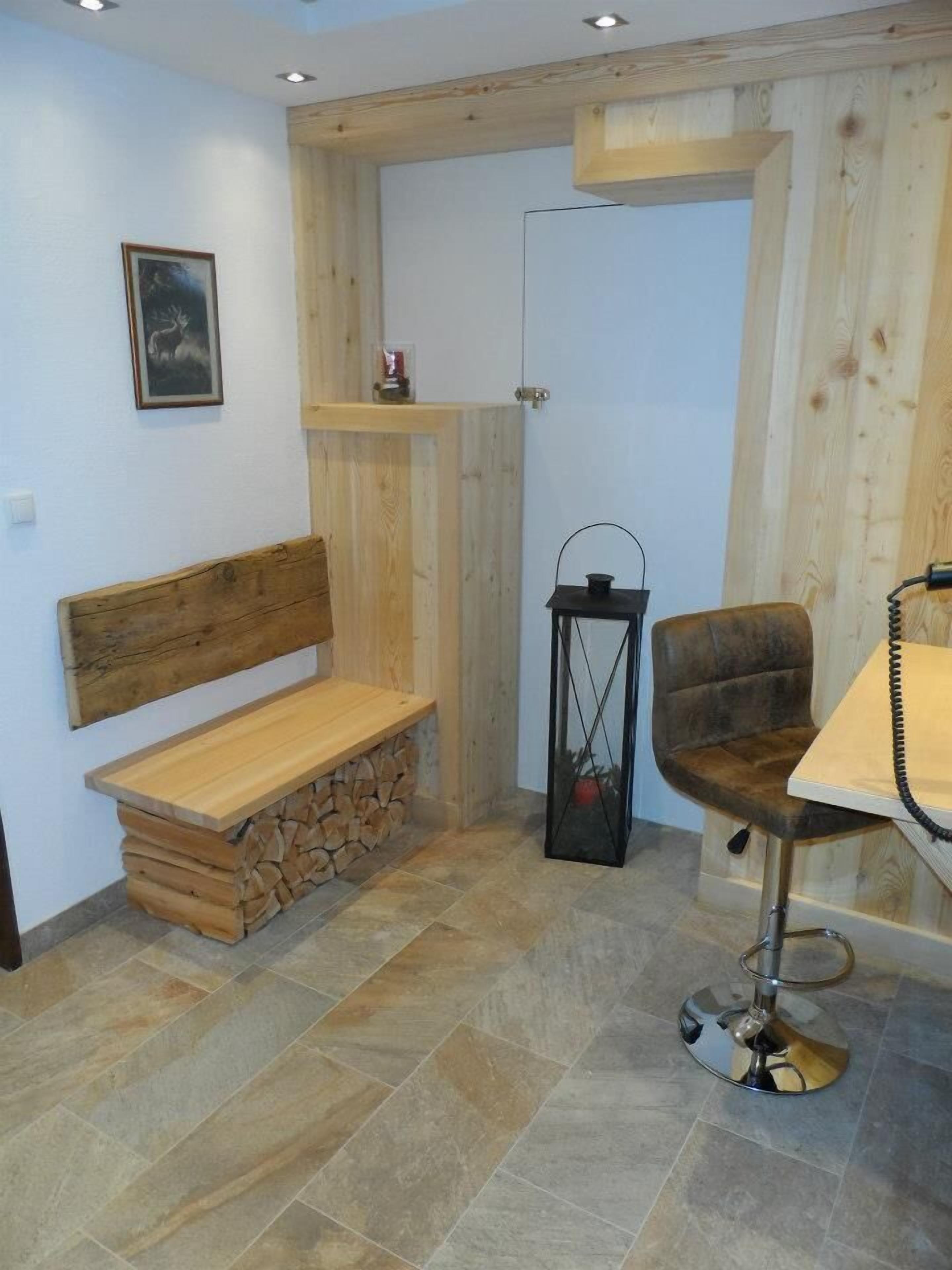 A cozy room with a wooden bench, a chair, a small table, and a lantern.