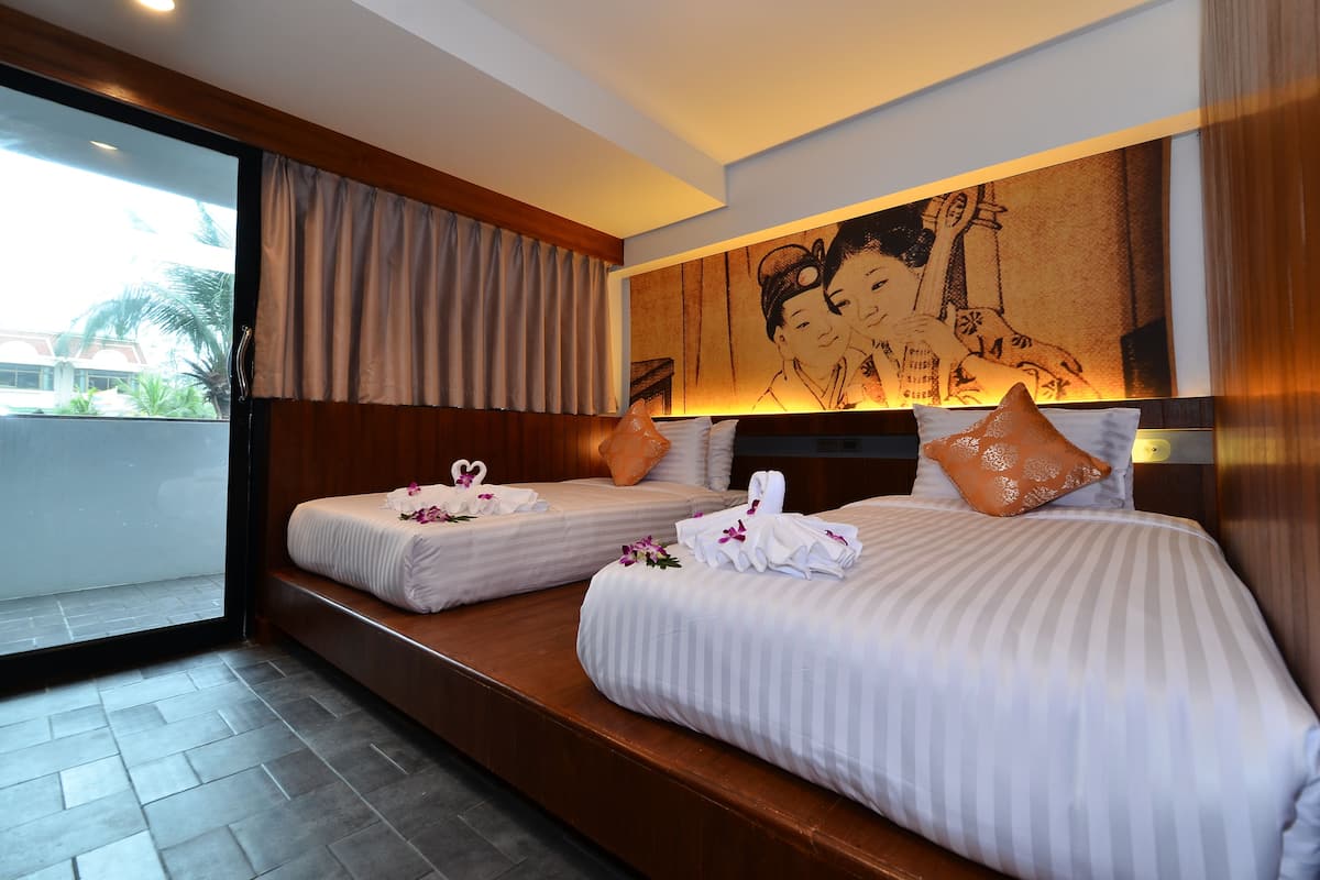 A hotel room with two beds, a large window, and a mural on the wall.