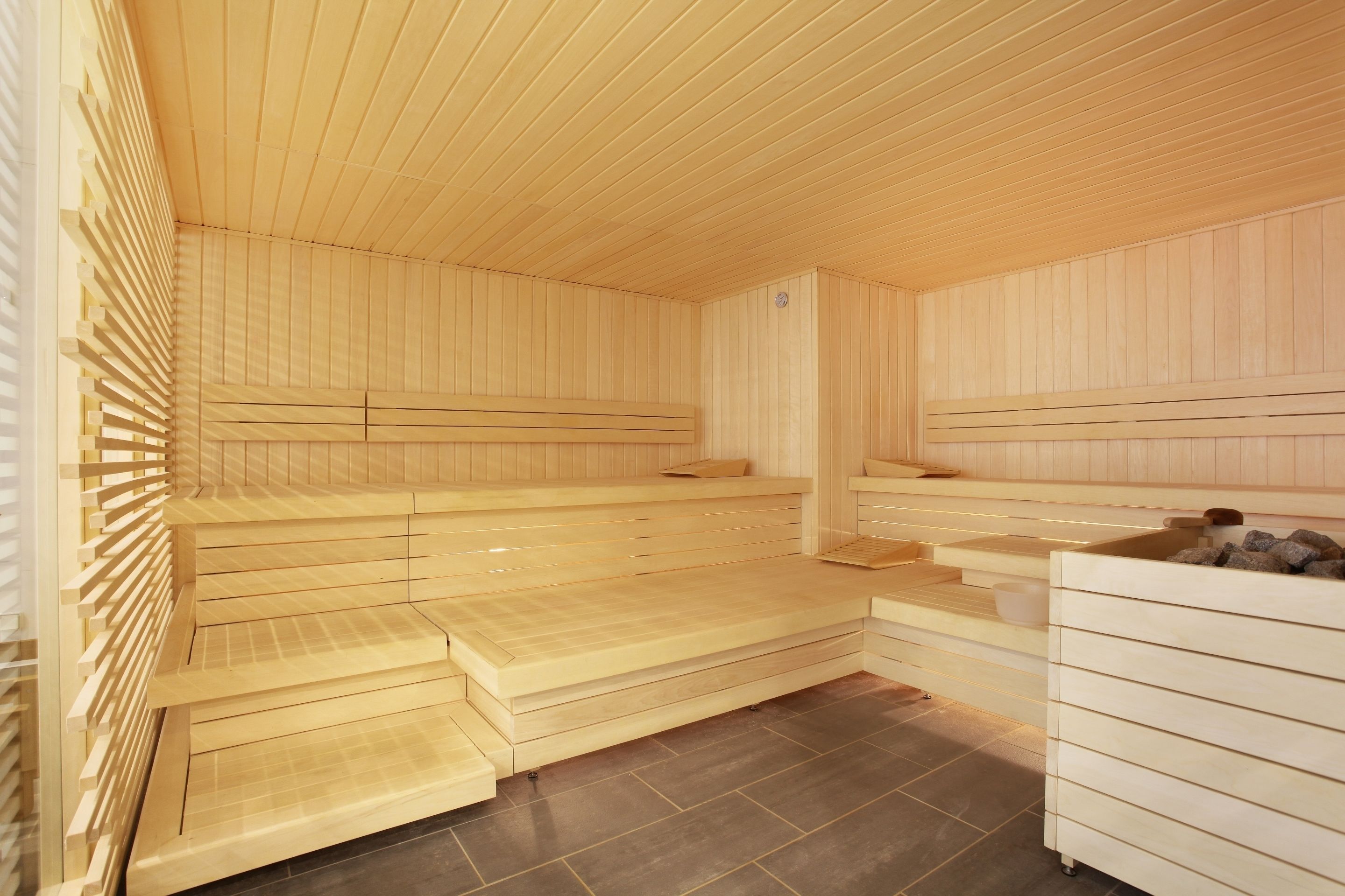 Eine Sauna mit Holzbänken und gefliestem Boden.