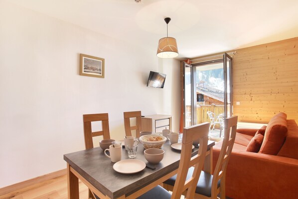 Un comedor con una mesa de madera, sillas y un tazón de cereal. Se ve una ventana con vistas a un paisaje nevado.