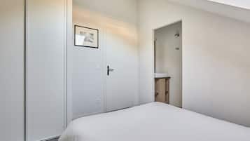 Une chambre d’hôtel avec un lit, une porte ornée d’un cadre de photo, une salle de bain avec un lavabo et un miroir.