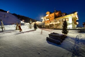 A snow-covered area with a building featuring balconies and a ski lift in the background.