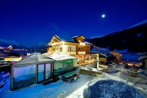 A snow-covered mountain resort with a large lodge featuring balconies and a well-lit entrance. - Hotel Alegra (Livigno)