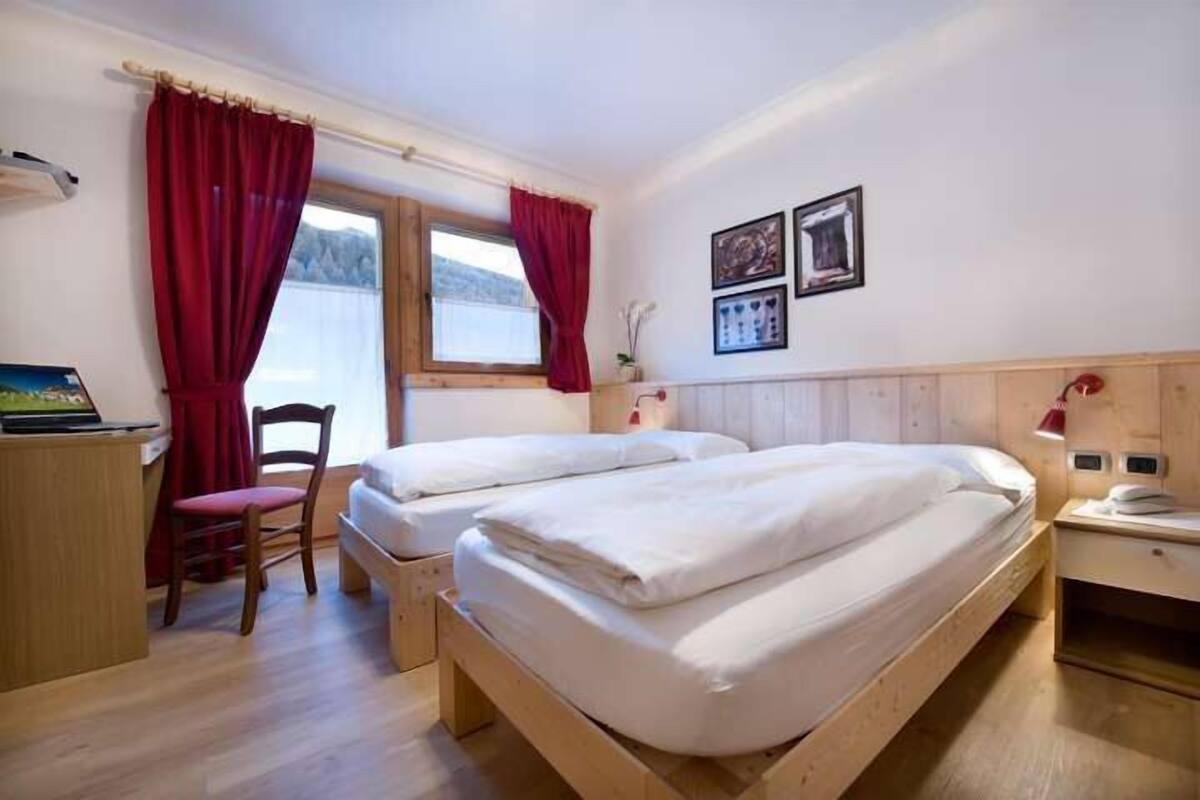 A bedroom with two beds, a desk, and a chair.