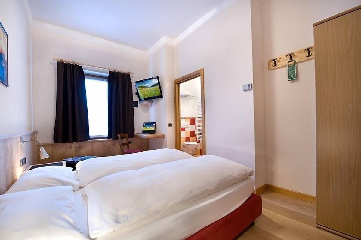 A hotel room with a bed, a TV, a desk, and a wardrobe.