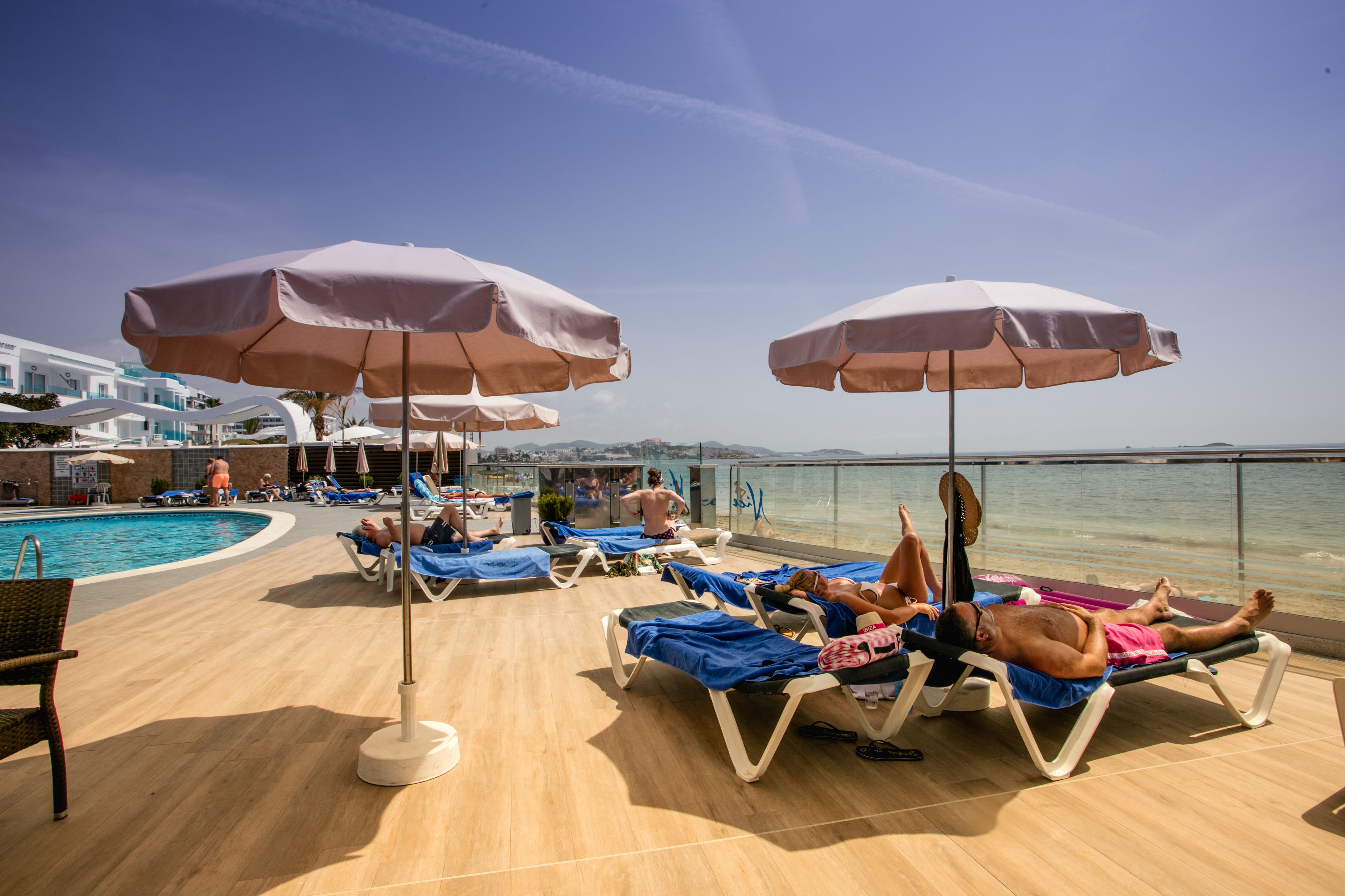 A cruise ship deck with sun loungers, umbrellas, and a pool.