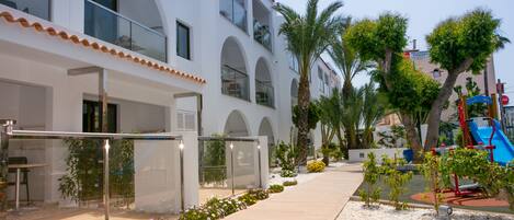 A modern building with a covered walkway, outdoor seating, and a playground.