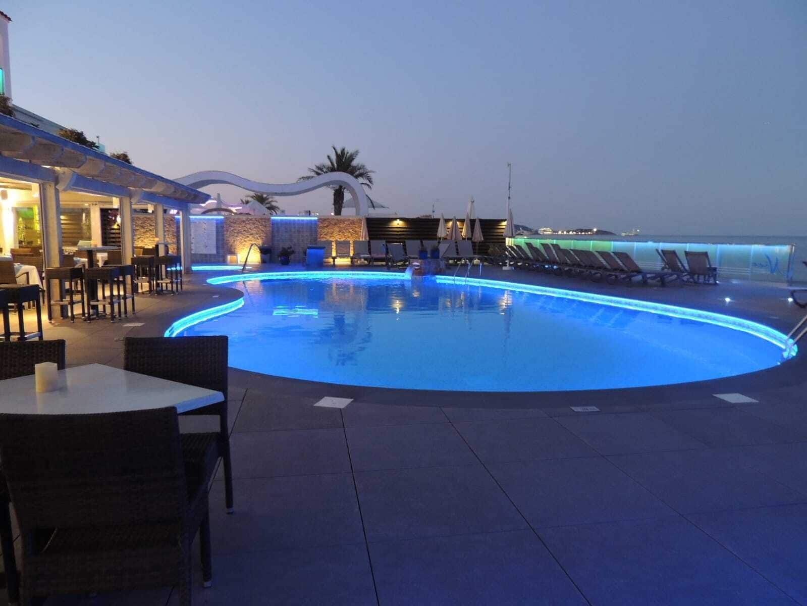 Un área de piscina con sillas de descanso y un restaurante.