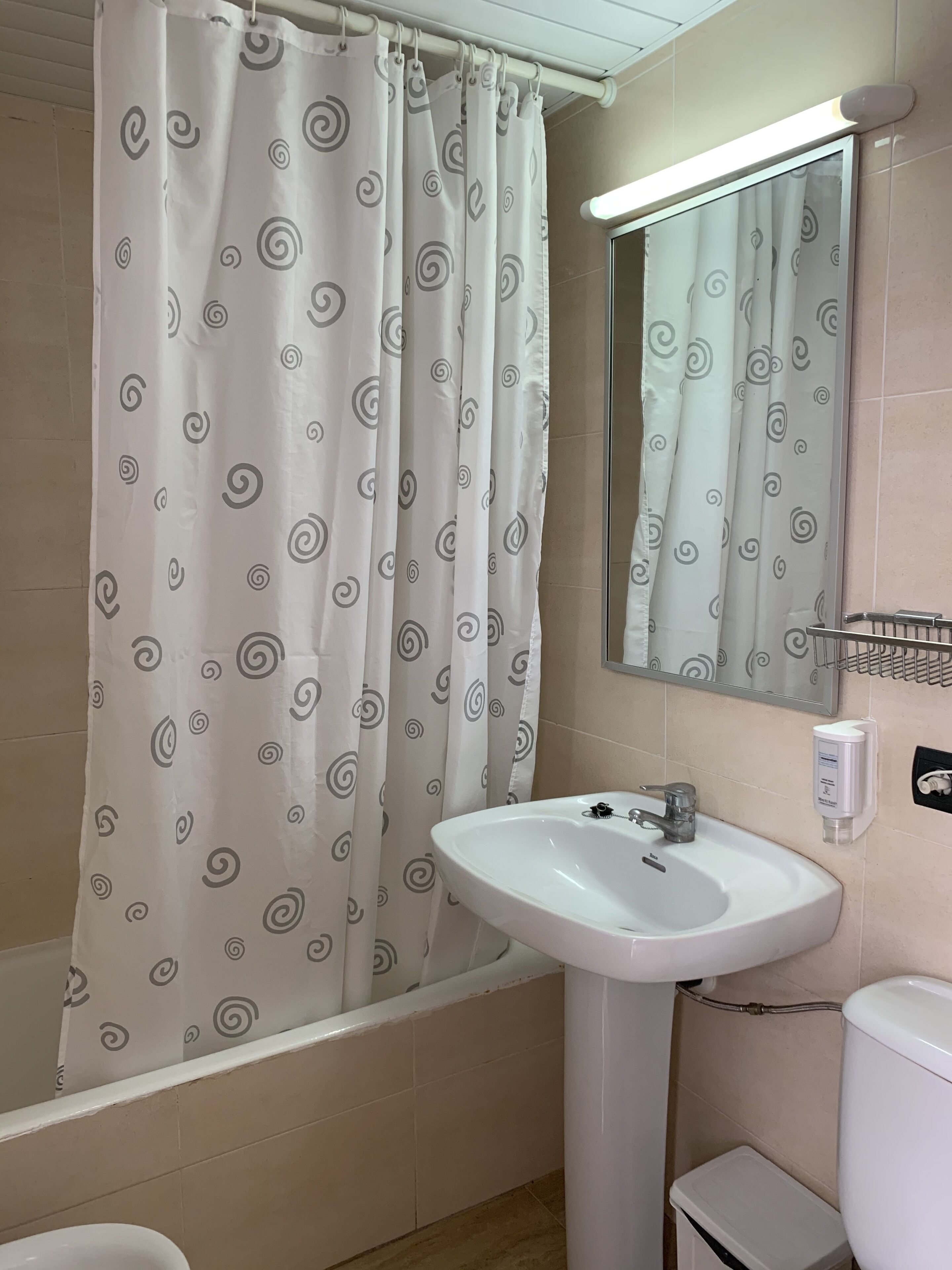 A bathroom with a bathtub, a sink, a toilet, and a mirror.
