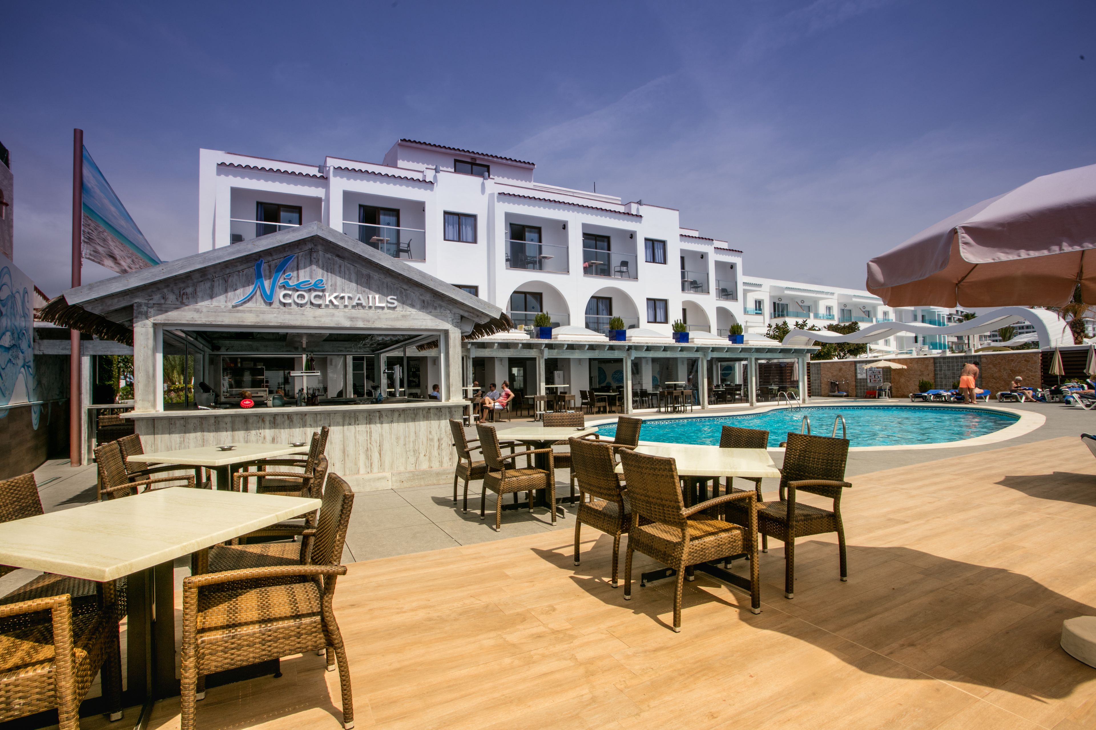 Eine Dachterrasse mit Korbmöbeln und einem Poolbereich.