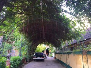 A covered pathway with a car parked at the end. - Royal thapae gate guesthouse (Chiang Mai)