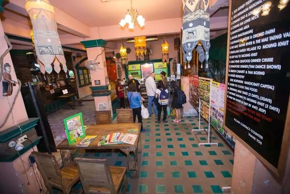 A restaurant with a green and white checkered floor, wooden tables, and hanging decorations. - Royal thapae gate guesthouse (Chiang Mai)