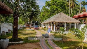 A pathway leading to a thatched-roof structure with a dining area visible inside. - Palm Resort Nilaveli (Nilaveli)