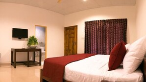 A bedroom with a bed, a desk, a television, and a door. - Palm Resort Nilaveli (Nilaveli)
