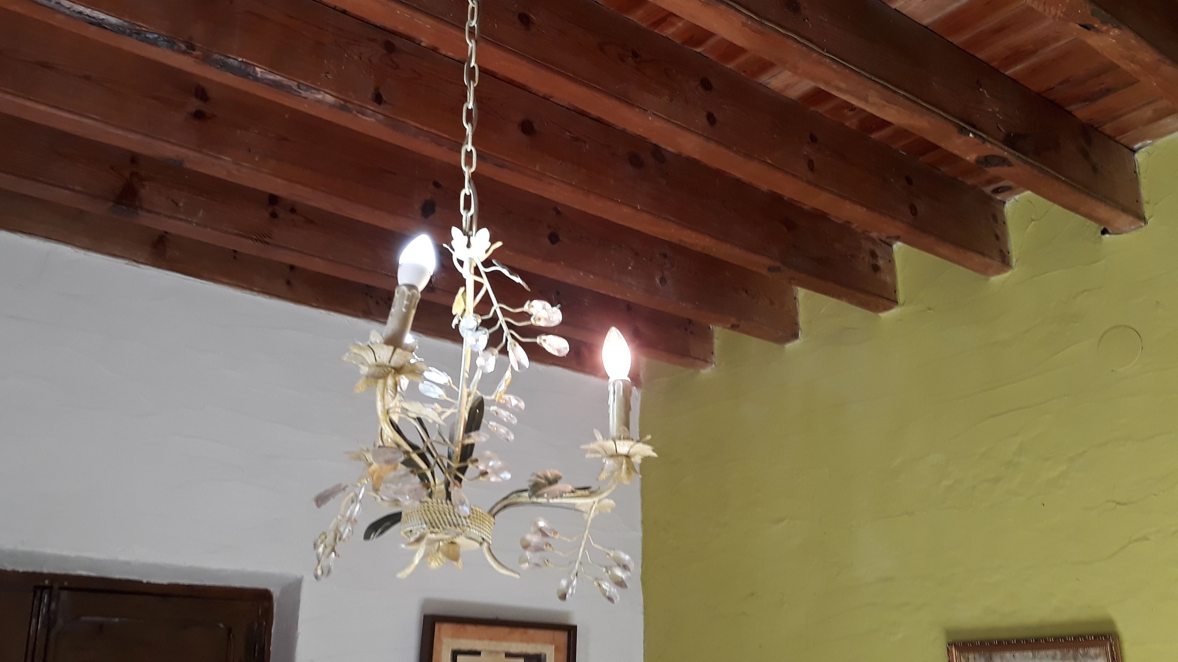 A chandelier with multiple candles hanging from a wooden ceiling.