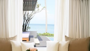 Une pièce avec vue sur la mer, un canapé avec des coussins et une petite table sur laquelle est posé un vase.