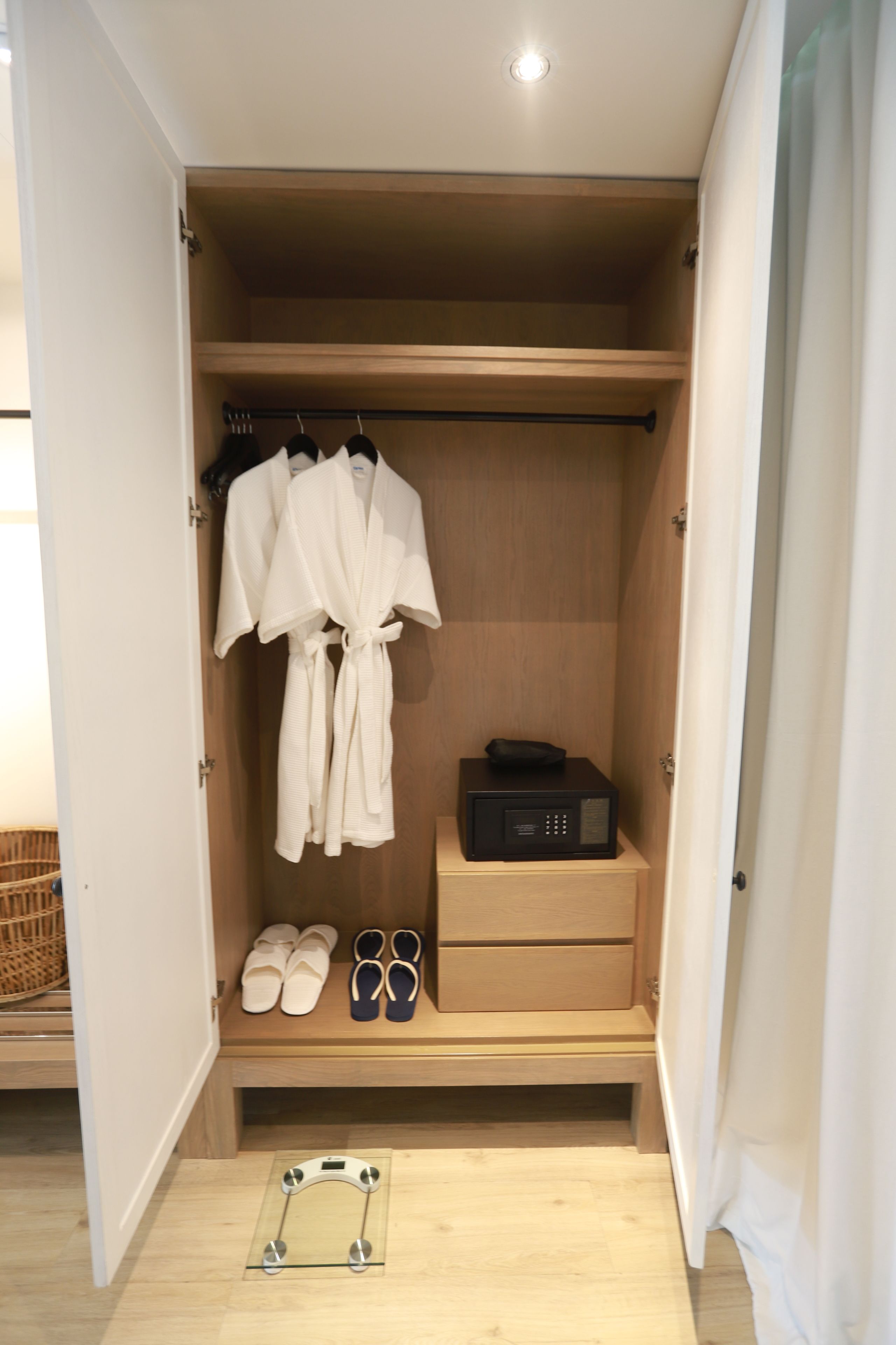 Een inloopkast met houten planken, een badjas, slippers en een radio.