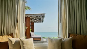 Une chambre avec vue sur la mer, une structure en bois à l’extérieur et un lit avec des oreillers.