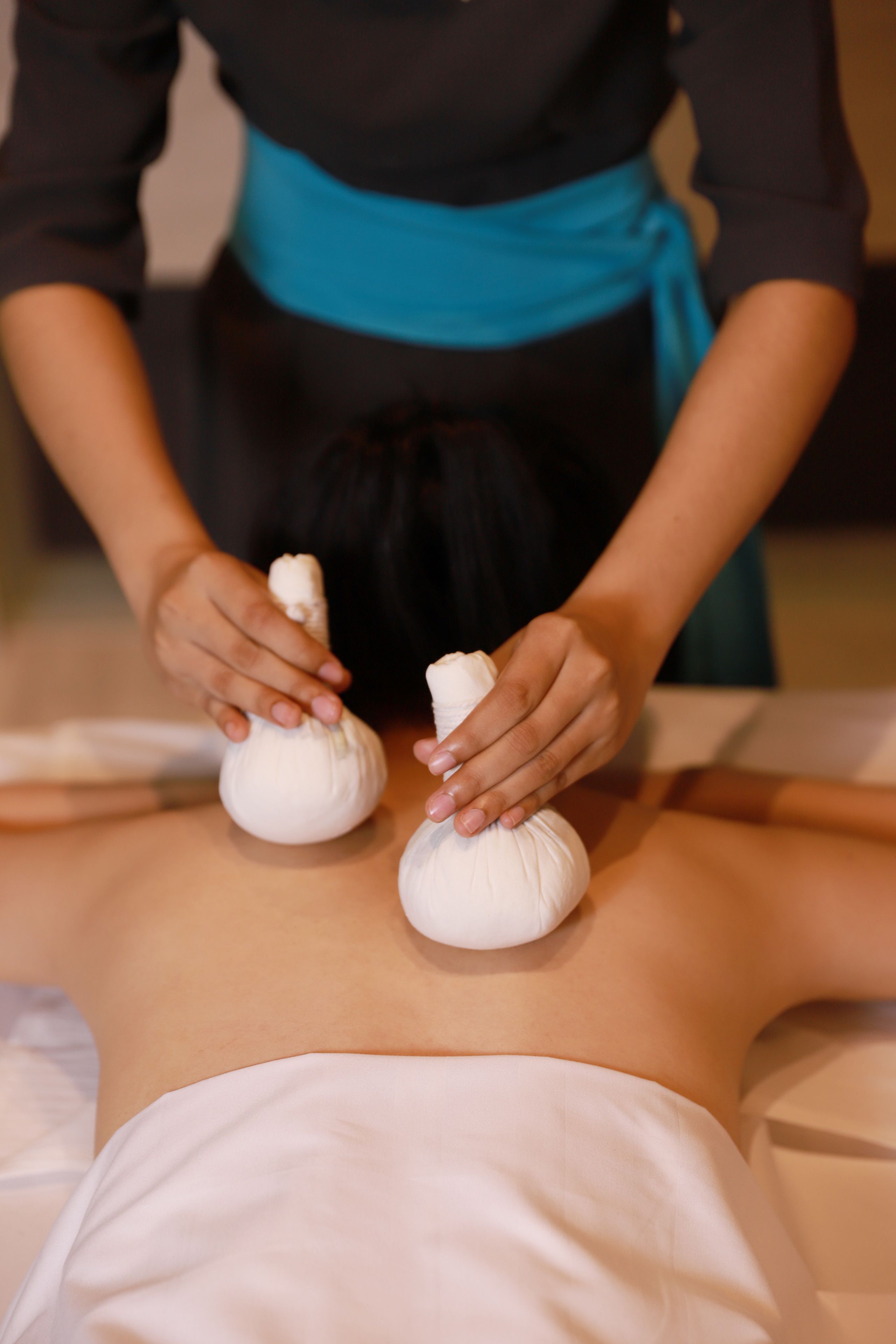 A person receiving a massage with two white massage balls on their back.