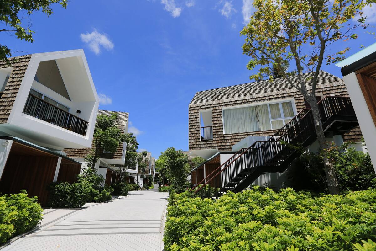 A modern residential building with a sloped roof, large windows, and a wooden deck.