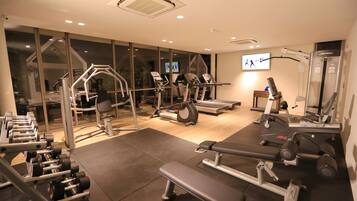 A gym with various exercise equipment, including treadmills, dumbbells, and weight machines.
