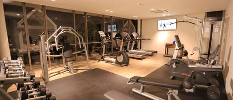 Un gimnasio con diversos equipos de ejercicio, incluyendo cintas de correr, mancuernas y máquinas de pesas.