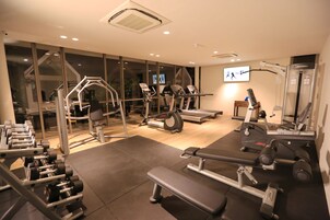 A gym with various exercise equipment, including treadmills, dumbbells, and weight machines.