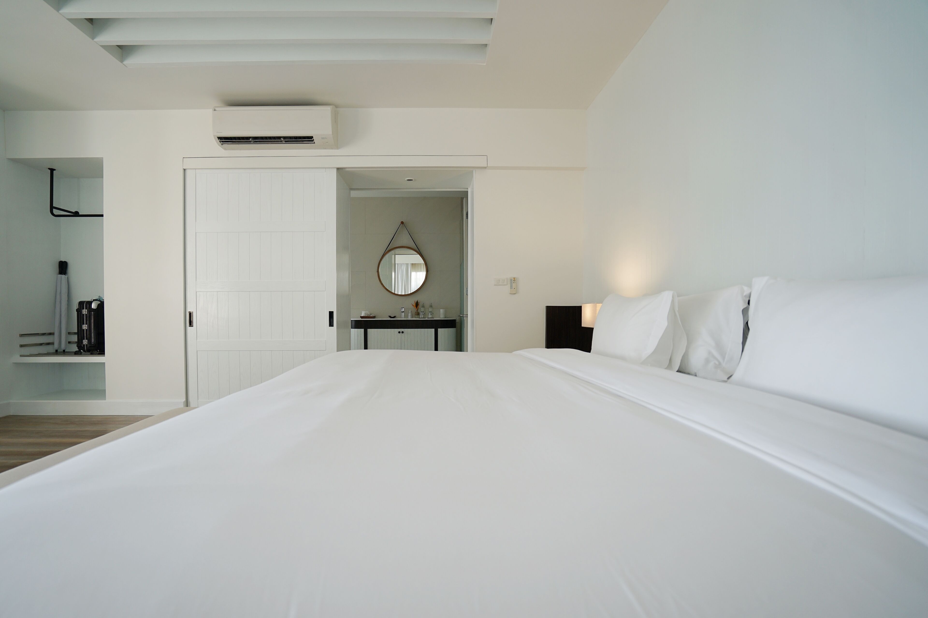 Habitación de hotel con una cama grande, un escritorio con espejo y un equipo de aire acondicionado en el techo.