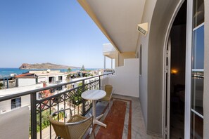A balcony with a view of the sea and a mountain, furnished with two chairs and a small table. - Manias Hotel Apartments (Chania)