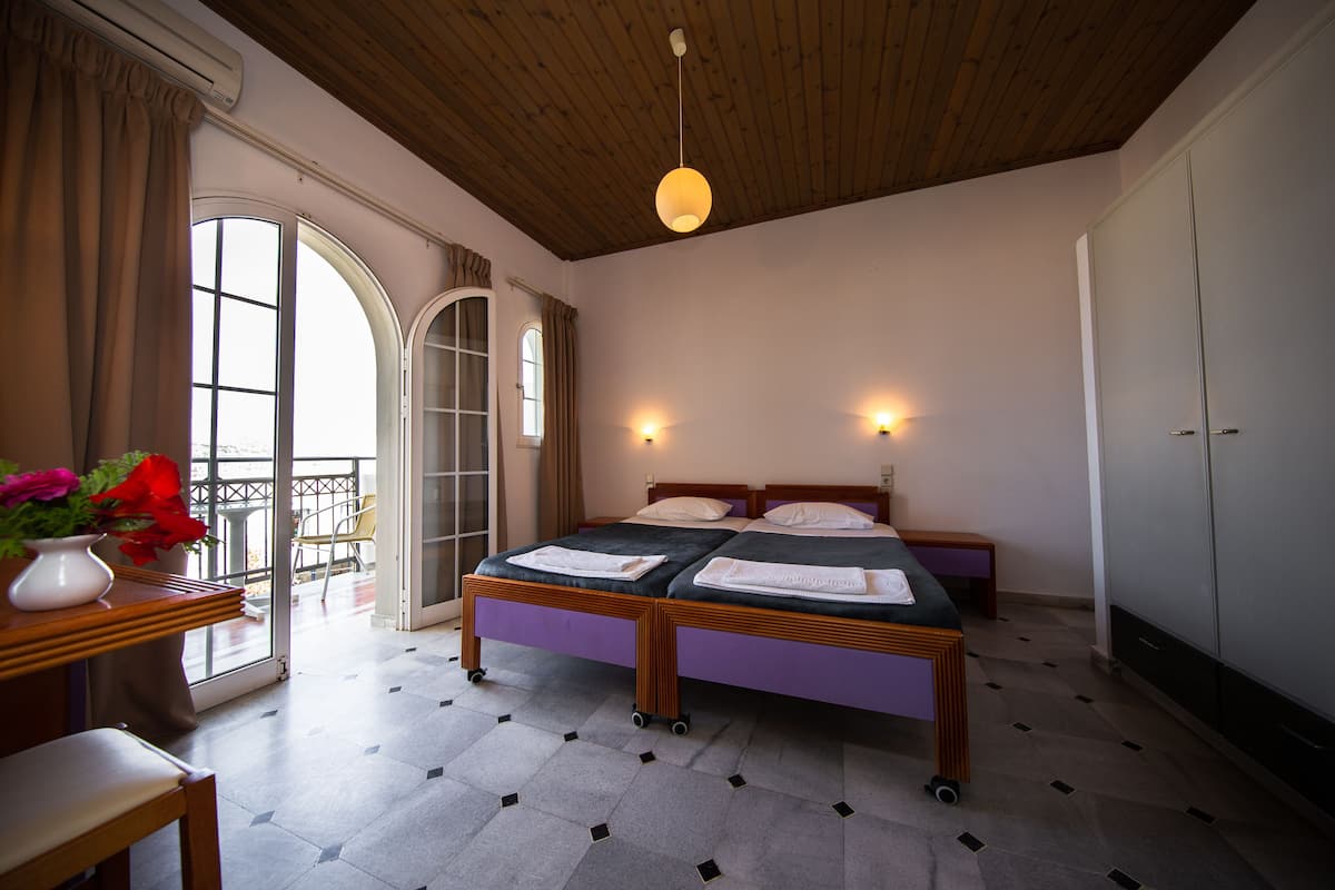 A bedroom with a bed, a wooden ceiling, a window, and a door.