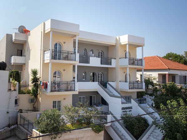 A multi-story residential building with balconies, a staircase, and a sign that reads "MANIAS". - Manias Hotel Apartments (Chania)