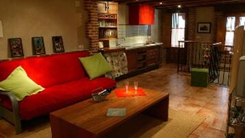 Una sala de estar acogedora con un sofá rojo, una mesa de centro de madera y una cocina al fondo.