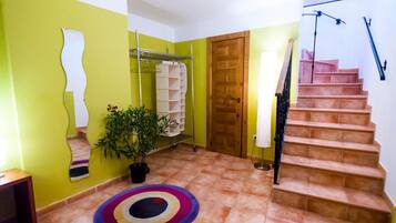 Un pasillo con una escalera, una planta en maceta y alfombras coloridas.