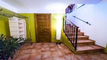 Gradi amb barana de fusta i barana metàl·lica, que condueix a una porta on penja una tovallola blanca.