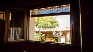 A room with a window overlooking a garden and a building with a tiled roof. - Villa Don Juan II (Segovia)