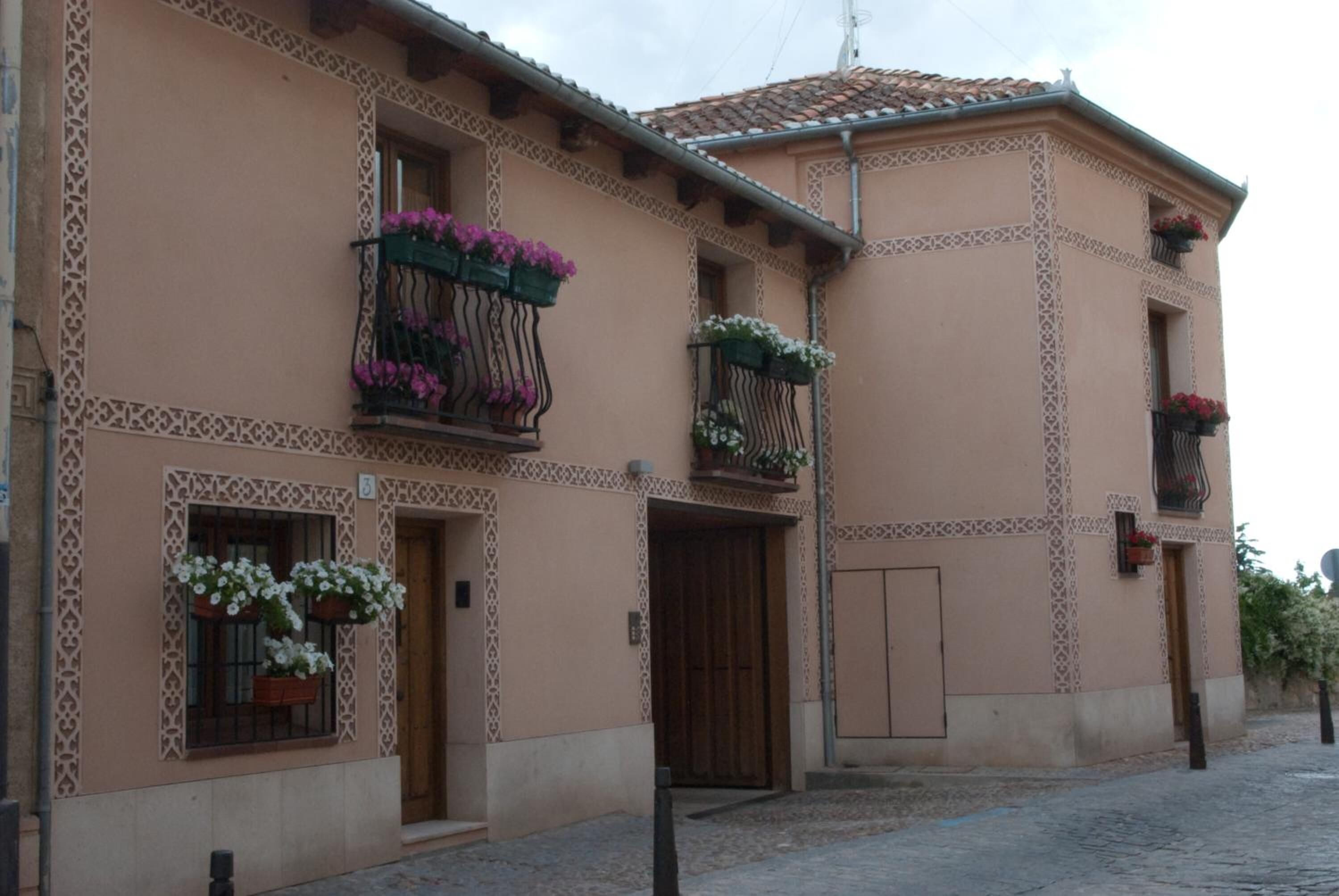 Un edificio de estilo arquitectónico tradicional, con balcones decorativos con jardineras y tejado de tejas.