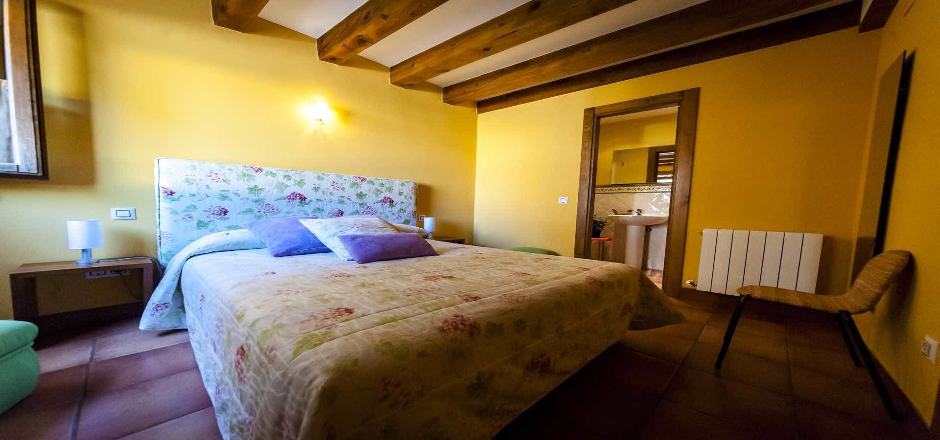 Ein Schlafzimmer mit Bett, Nachttisch, Stuhl und angrenzendem Badezimmer.