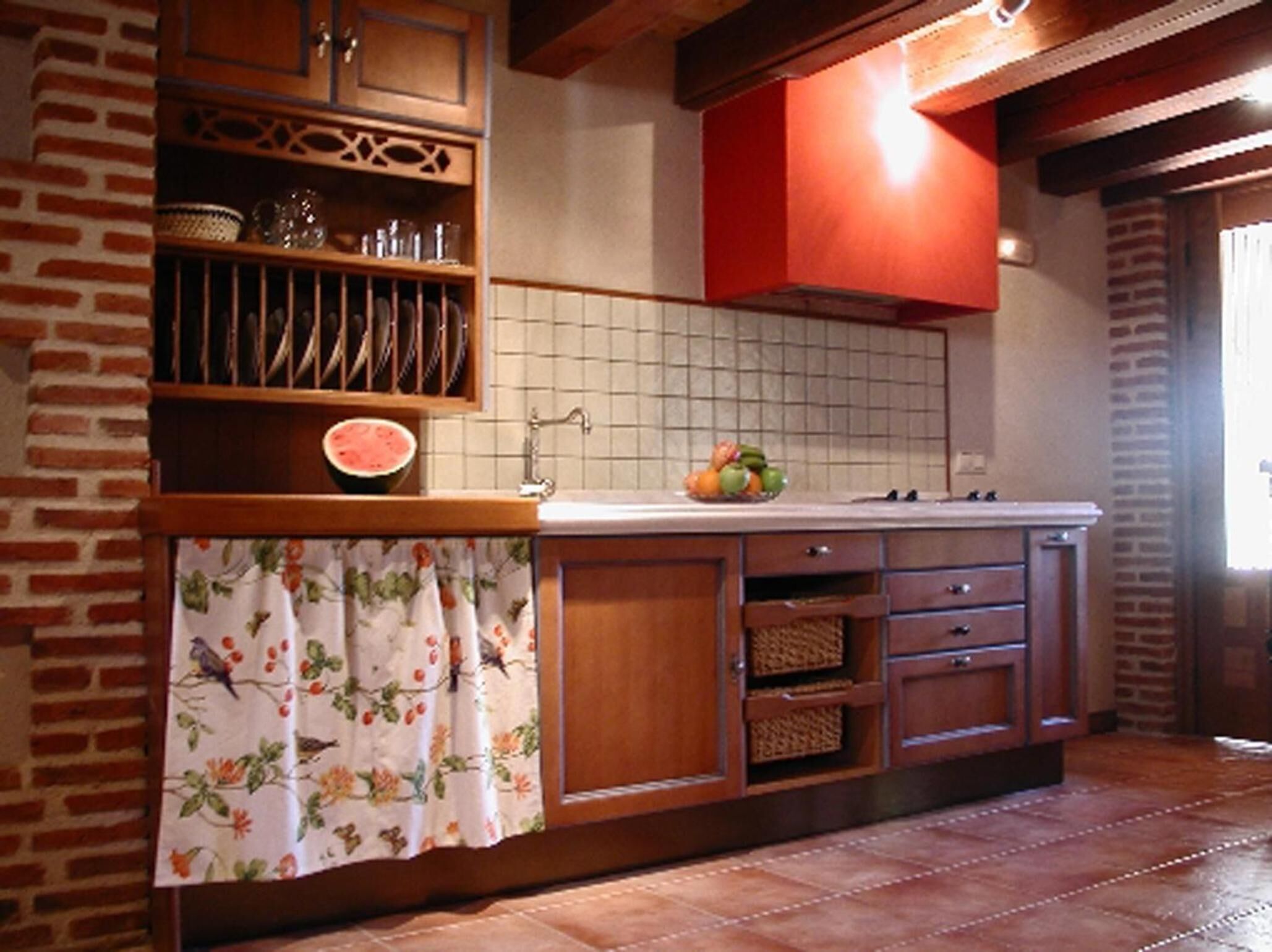 Una cocina con armarios de madera, salpicadero de azulejos y encimera con cesta de frutas.