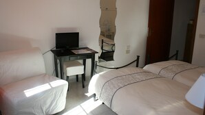 Une chambre d’hôtel avec deux lits, un bureau avec un ordinateur, une chaise et une porte.