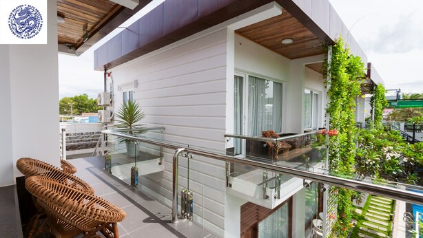 A modern apartment with a balcony, glass railings, and a view of a pool. - Hotel Blue Dragon (Phu Quoc)