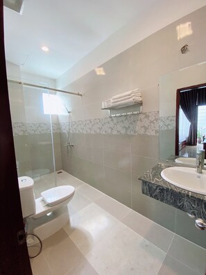 Een moderne badkamer met een douchecabine van glas, een toilet en een wastafel met een marmeren afwerking.