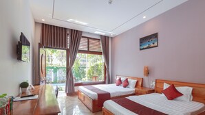 A hotel room with two beds, a wooden desk, a TV, and a window with curtains. - Hotel Blue Dragon (Phu Quoc)