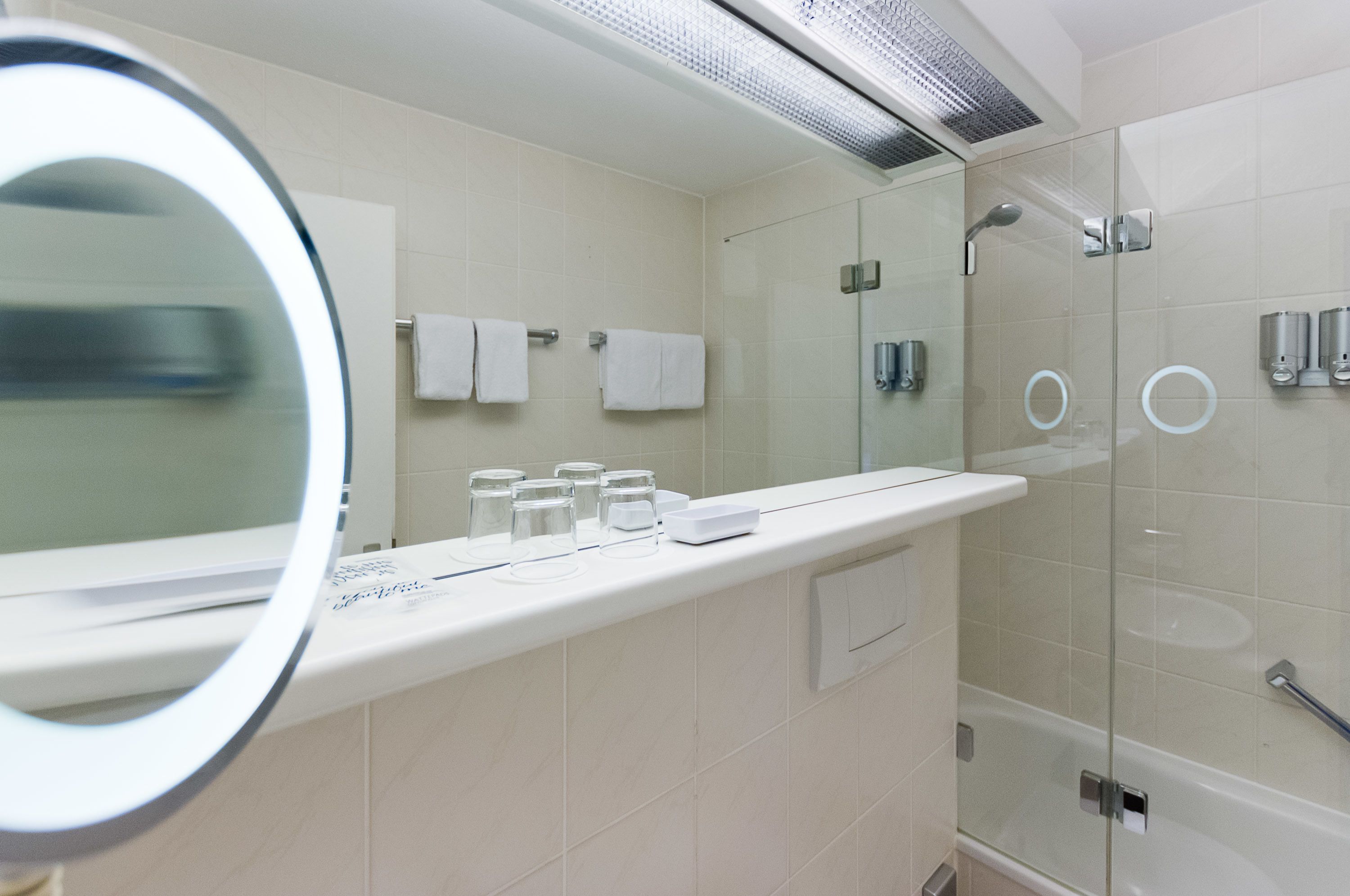 A modern bathroom with a glass shower enclosure, a white vanity with a mirror, and a towel rack.
