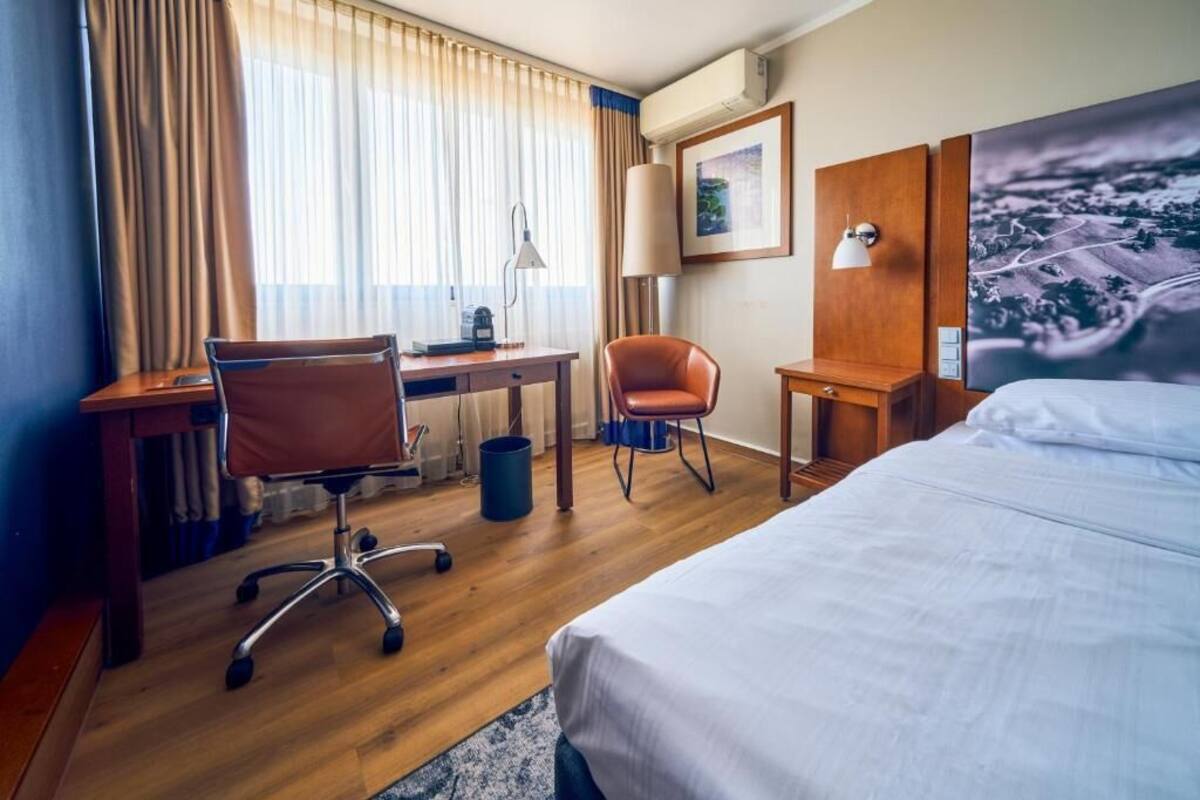 Ein Hotelzimmer mit Bett, Schreibtisch, Bürostuhl und Sessel.
